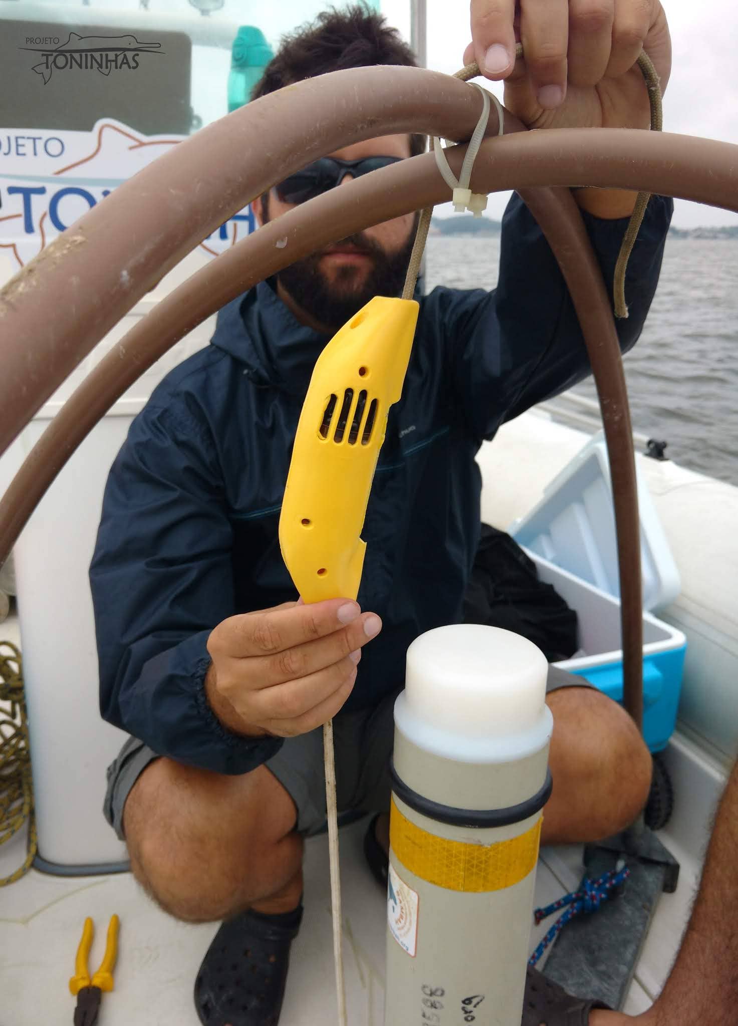 Pesquisador do Toninhas do Brasil instalando um alarme acústico para toninhas em um módulo de pesquisa.