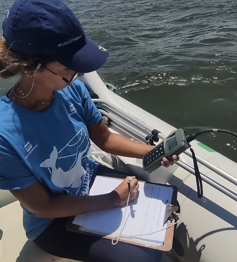 Toninhas do Brasil researcher on board a vessel with a clipboard and GPS equipment during a field trip.