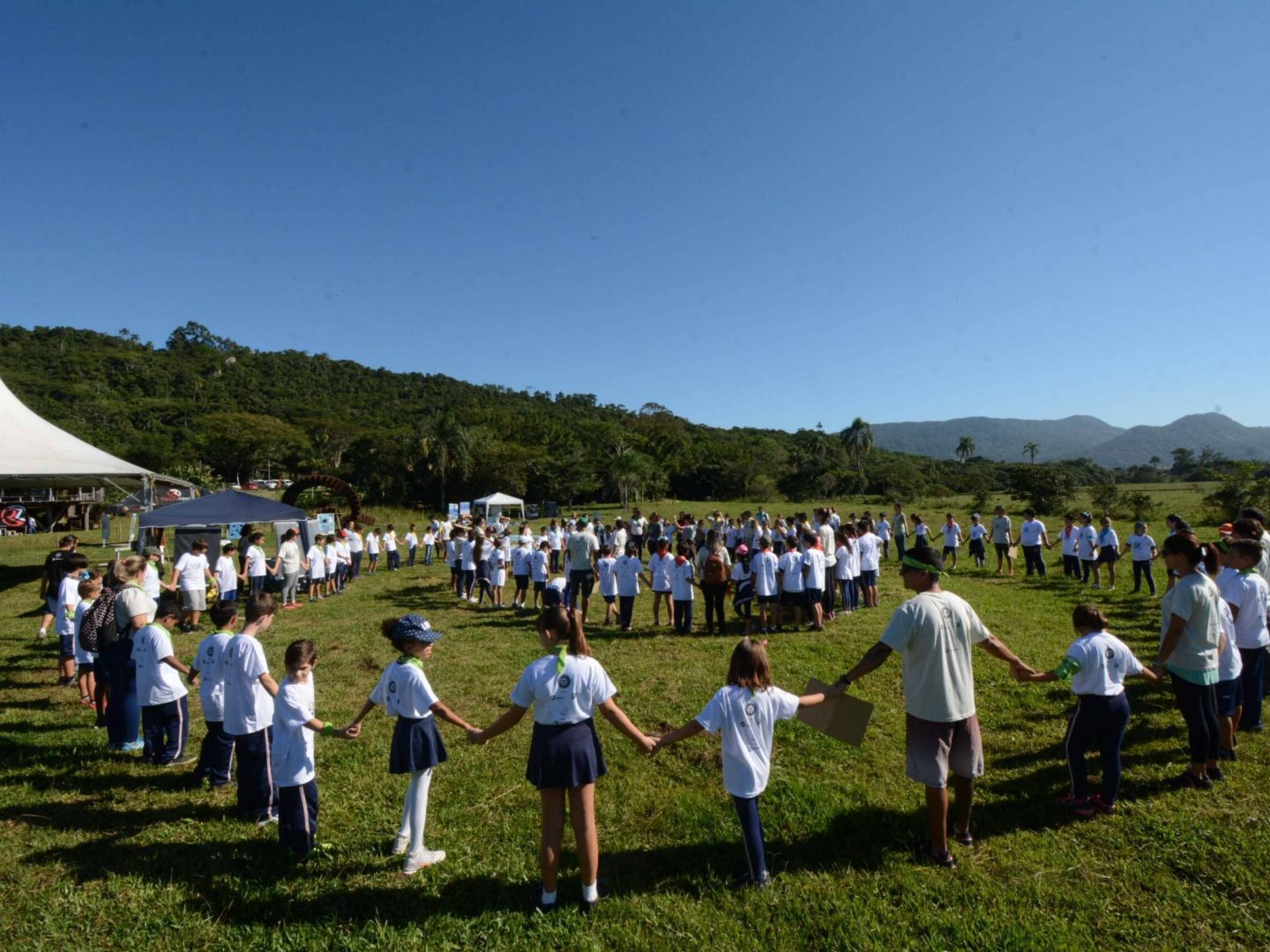 Grupo de cerca de 50 crianças brincam de roda em dois círculos no gramado durante o evento maratoninha que aconteceu em Garopaba (SC) em 2018.